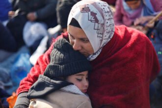 Seorang wanita Palestina memeluk seorang anak menunggu untuk diizinkan kembali ke rumah mereka di Gaza utara (Dok. Reuters)