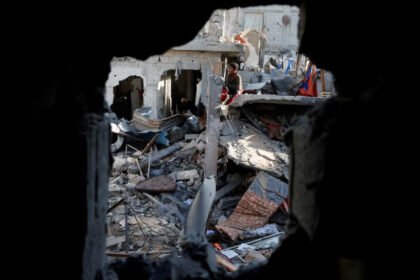 Seorang anak duduk di tengah reruntuhan bangunan saat warga Palestina memeriksa lokasi serangan Israel terhadap sebuah rumah di Khan Younis di Jalur Gaza selatan, (18--3-2025) (Dok. Reuters)