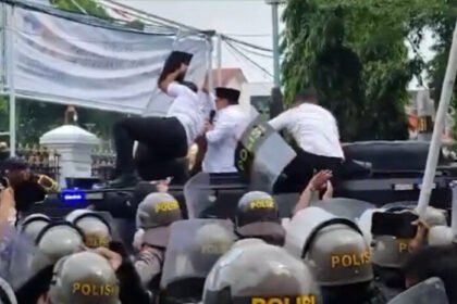 Bupati Pati Sudewo mengenakan kemeja putih dan peci hitam, dilempari sandal saat mencoba meminta maaf di tengah aksi besar menuntut dirinya mundur dari jabatan.