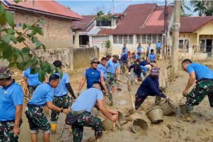 TNI AU dan warga bergotong royong membersihkan sisa lumpur banjir di Komplek Banda Gadang Permai.