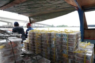 Perahu kecil mengangkut paket Makan Bergizi Gratis menyeberangi Sungai Musi untuk didistribusikan ke sekolah-sekolah di wilayah Gandus, Palembang.