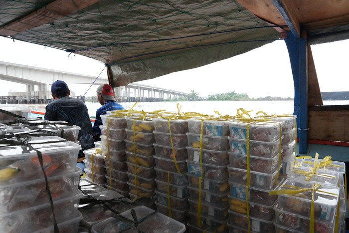 Perahu kecil mengangkut paket Makan Bergizi Gratis menyeberangi Sungai Musi untuk didistribusikan ke sekolah-sekolah di wilayah Gandus, Palembang.