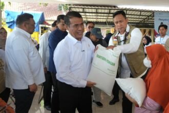 Kepala Bapanas Andi Amran Sulaiman dan Dirut BULOG Ahmad Rizal Ramdhani menyerahkan bantuan beras kepada warga di Kelurahan Lidah Kulon, Surabaya, Rabu (12/8/2026).