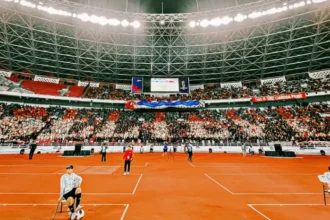 Ribuan suporter Timnas Indonesia membentuk koreografi 'BELIEVE' menggunakan jas hujan merah dan putih di tribun SUGBK.
