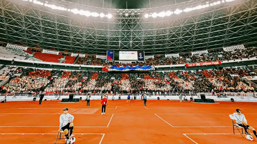 Ribuan suporter Timnas Indonesia membentuk koreografi 'BELIEVE' menggunakan jas hujan merah dan putih di tribun SUGBK.
